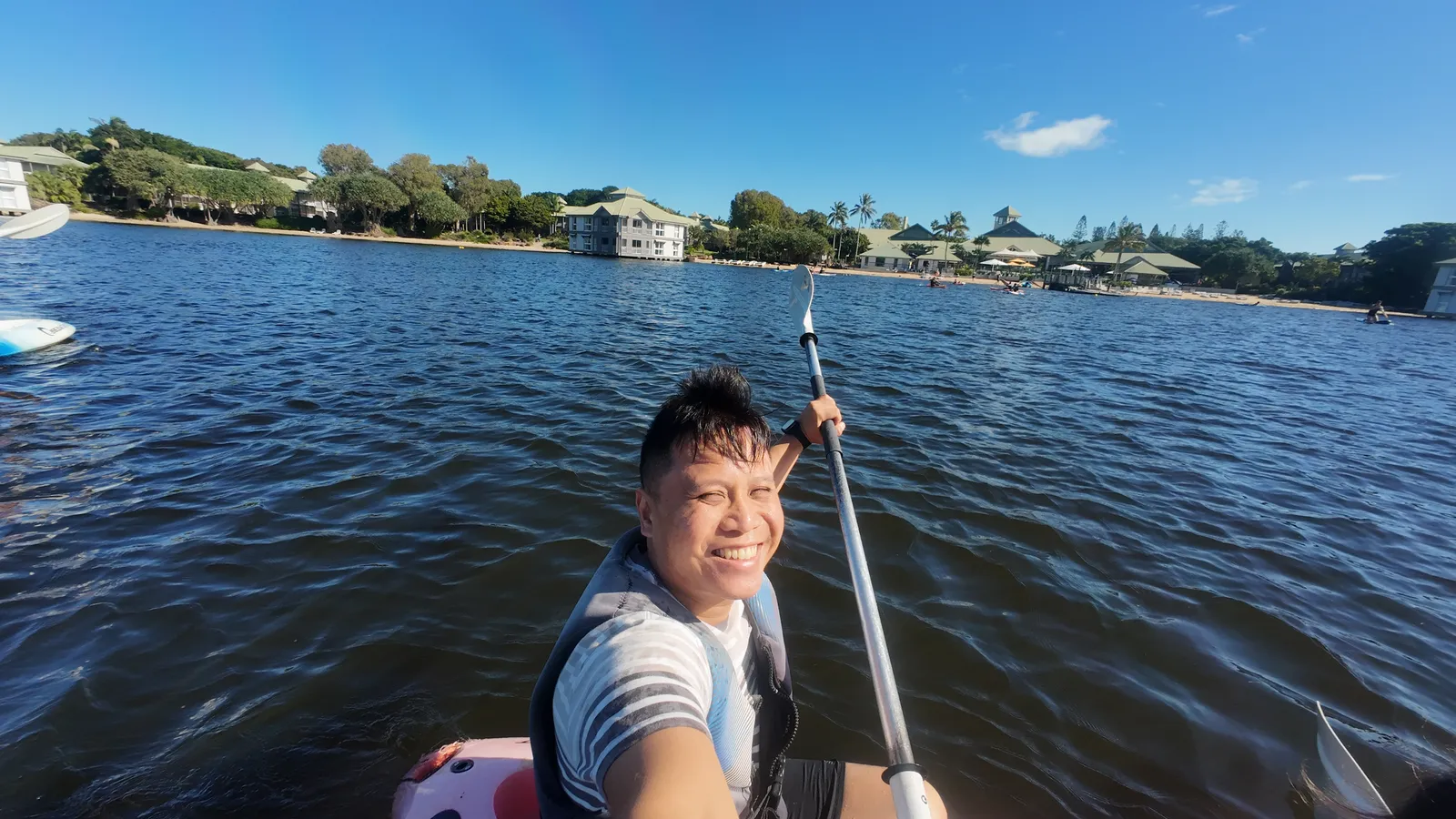 Zhi Lee kayaking on calm water, holding a paddle and smiling